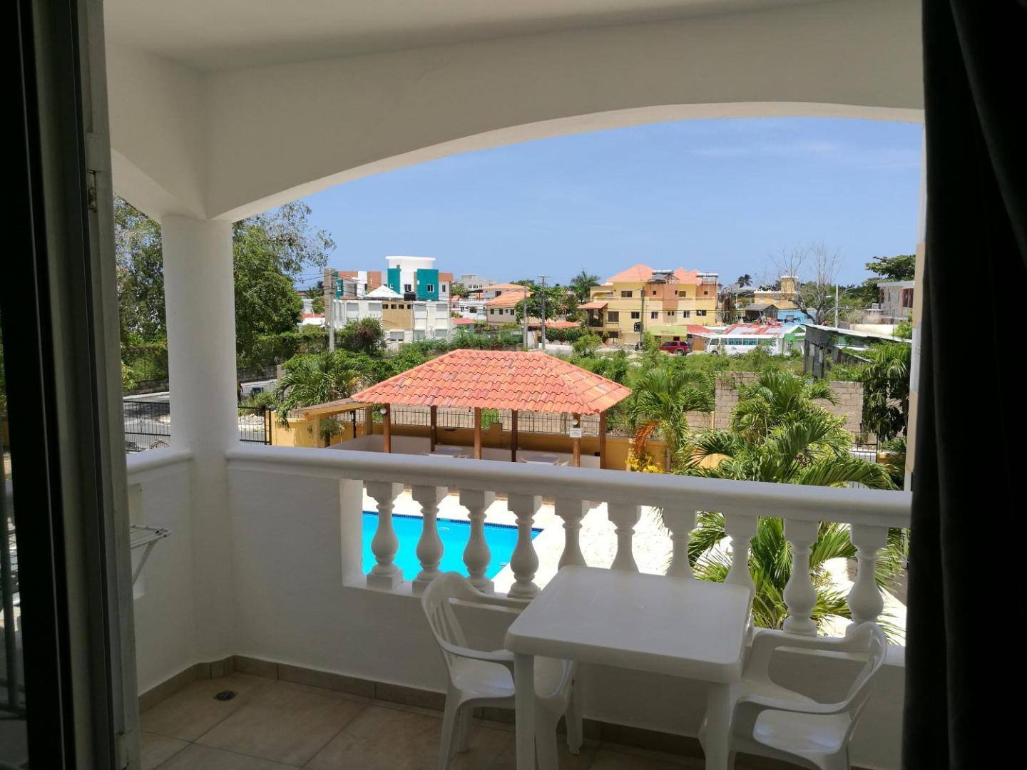 Balcony with a small table and chairs overlooking the pool and the village