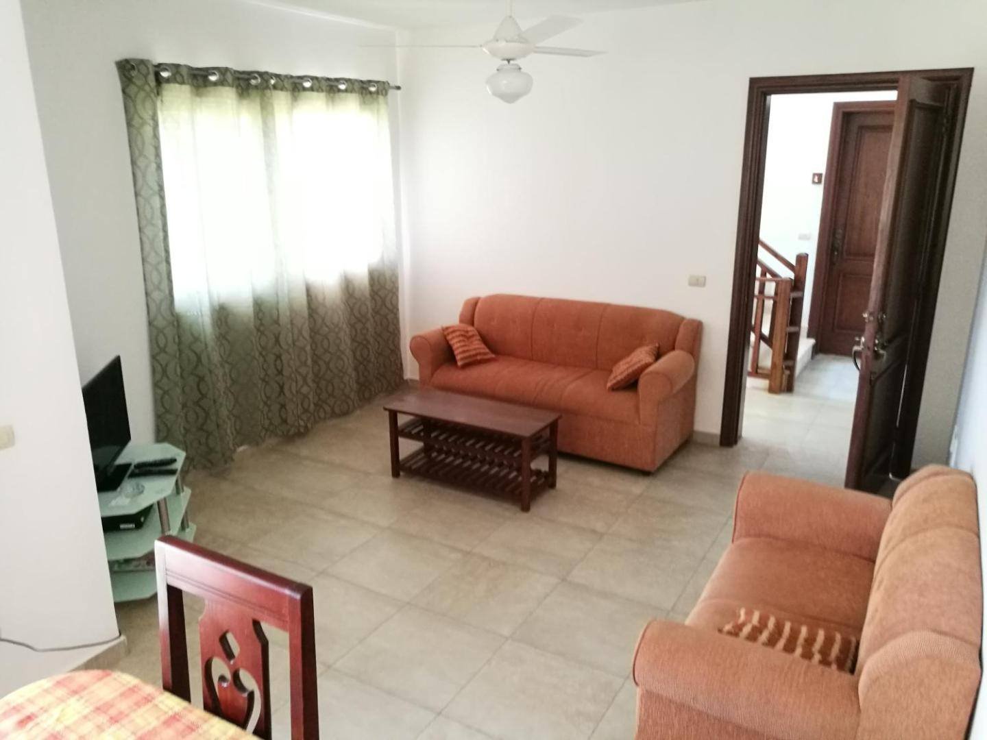 Apartment living room with orange sofas, a coffee table and a dining set
