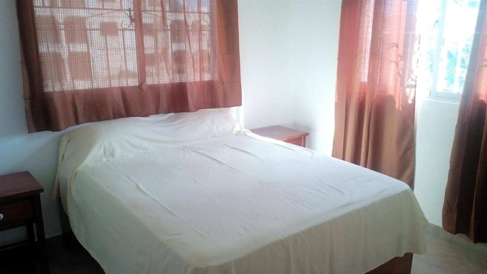 Bright bedroom with a double bed and a window with curtains